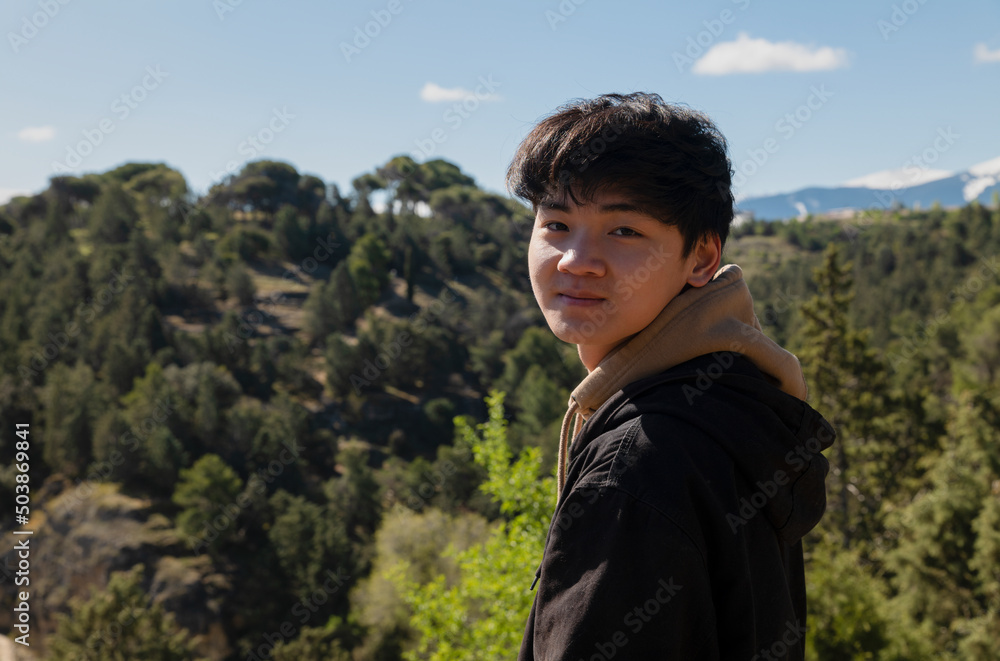 Portrait of teenage Asian boy against forest and sky Portrait of teenage Asian boy against forest and sky