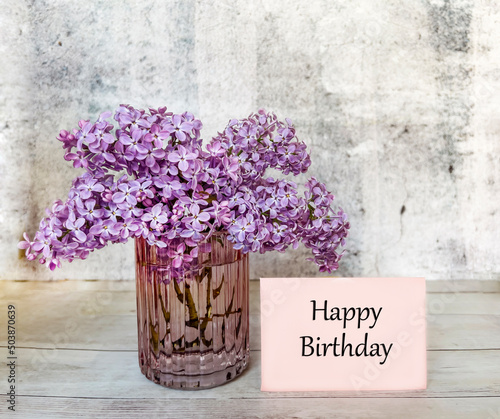 Happy Birthday Greeting  Card with Purple Lilac Flowers in Vase. Happy Birthday Message on Pink Card 