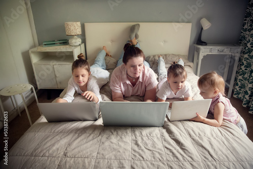 Mom with kids in real bedroom with laptops