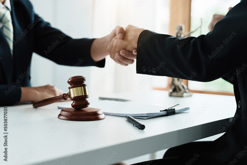 Law, consultation, agreement, contract, lawyer or attorney shakes hands to agree on the client's offer to be hired to fight the parties in court. Law, consultation, agreement, contract, lawyer or attorney shakes hands to agree on the client's offer to be hired to fight the parties in court.