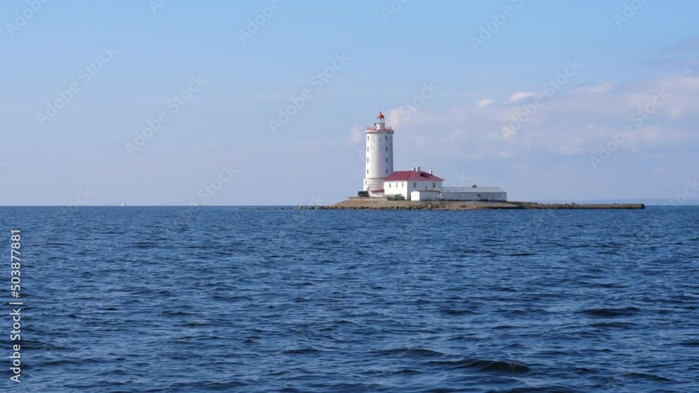 Lighthouse Tolobukhin located on small isle near Kronshtadt island, old fortified navigational light building. Calm waters of Gulf of Finland on fore. Light-keeper house seen near thick white tower Lighthouse Tolobukhin located on small isle near Kronshtadt island, old fortified navigational light building. Calm waters of Gulf of Finland on fore. Light-keeper house seen near thick white tower