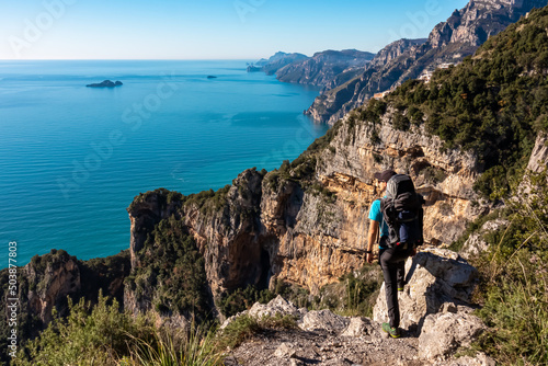 Man with panoramic view from hiking trail Path of Gods between coastal towns Positano and Praiano. Trekking in Lattari Mountains, Apennines, Amalfi Coast, Campania, Italy, Europe. Mediterranean Sea