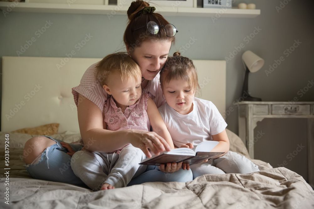 Mom with children in the bedroom reading a book, lifestyle Mom with children in the bedroom reading a book, lifestyle