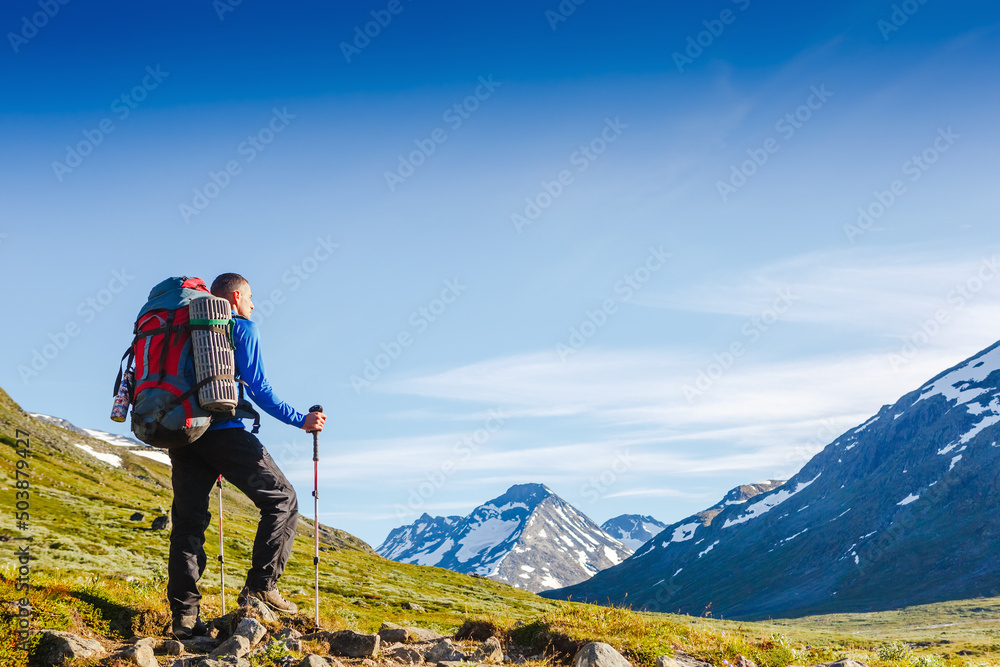 Naklejka premium Hiker hiking with backpack looking at mountain view. Norway landscape