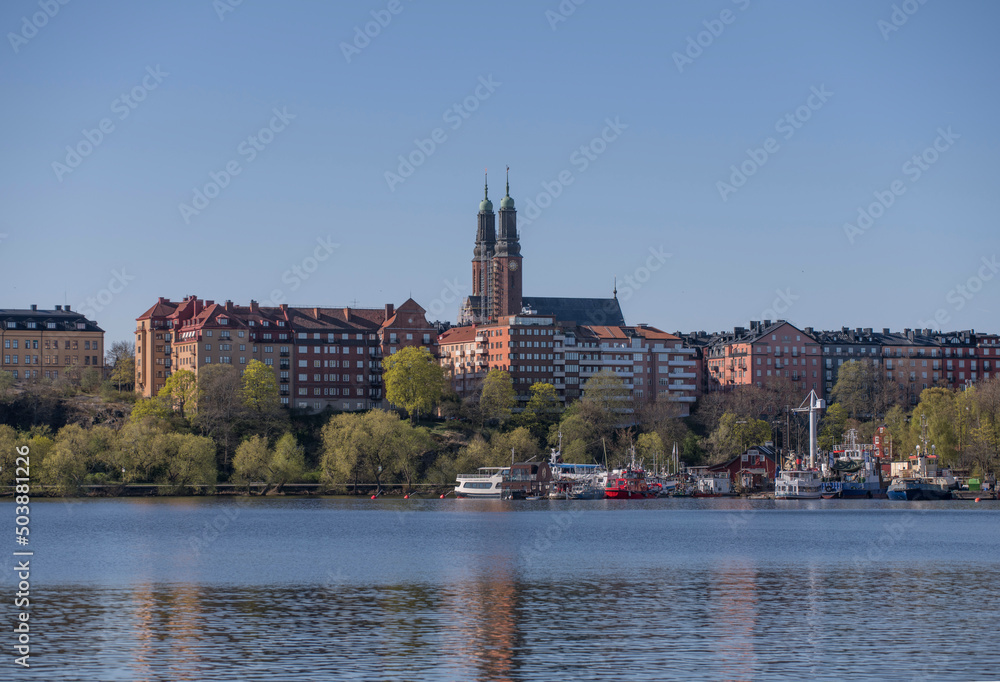 View over the Bay Riddarfjärden with churches and apartment buildings over a with wharfed boats a sunny spring day in Stockholm View over the Bay Riddarfjärden with churches and apartment buildings over a with wharfed boats a sunny spring day in Stockholm