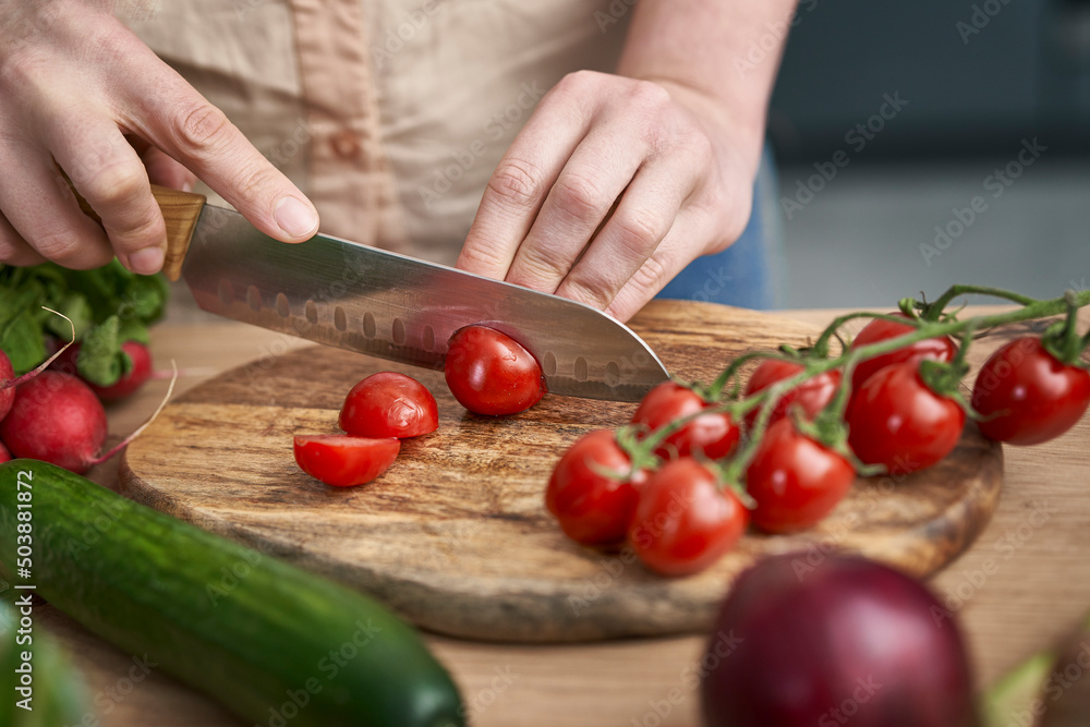 Woman cutting cherry tomatoes on wooden board Woman cutting cherry tomatoes on wooden board