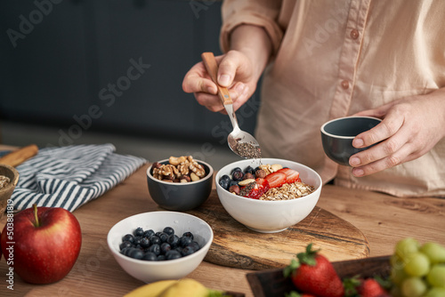 Woman adding seeds to bowl of muesli
