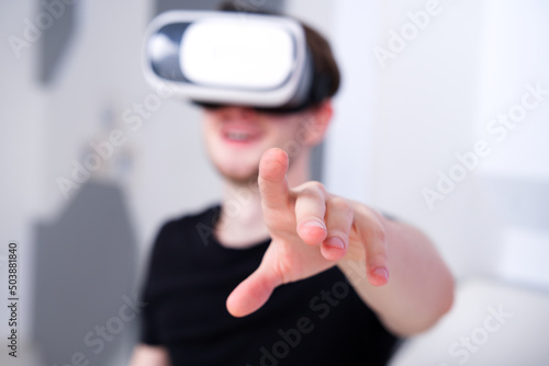 Portrait of happy young handsome man  positive smiling guy using  wearing a modern device virtual reality headset mask or 3D  AR  VR glasses  playing the game. People and technology metaverse concept