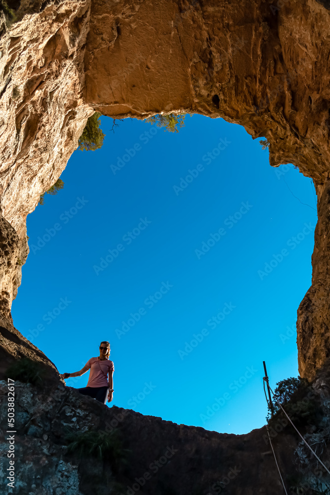 Hiking woman standing in hole of rock formation Montepertuso Il Buco on hiking trail Path of Gods between Positano and Praiano, Amalfi Coast, Campania, Italy, Europe. Cliff rock at Mediterranean Sea