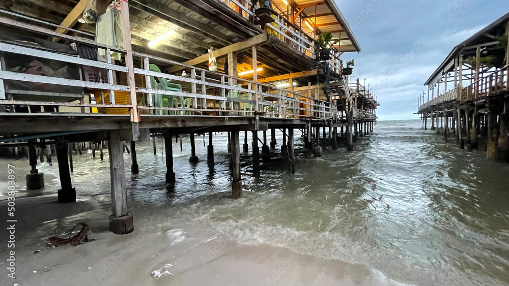 Maisons sur pilotis dans le quartier des pêcheurs de Hua Hin. La marée haute s'engouffre sous les maisons en bois entre les supports en bois Maisons sur pilotis dans le quartier des pêcheurs de Hua Hin. La marée haute s'engouffre sous les maisons en bois entre les supports en bois