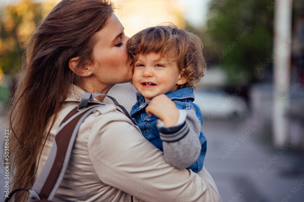 Young mother holding her son, giving him kisses on the head. Young mother holding her son, giving him kisses on the head.