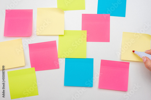 Blank Sticker notes on white background. hand with red marker ready to write. Mockup sticky Note Paper. empty sheets for notes on white bulletin board. Colored sticky notes