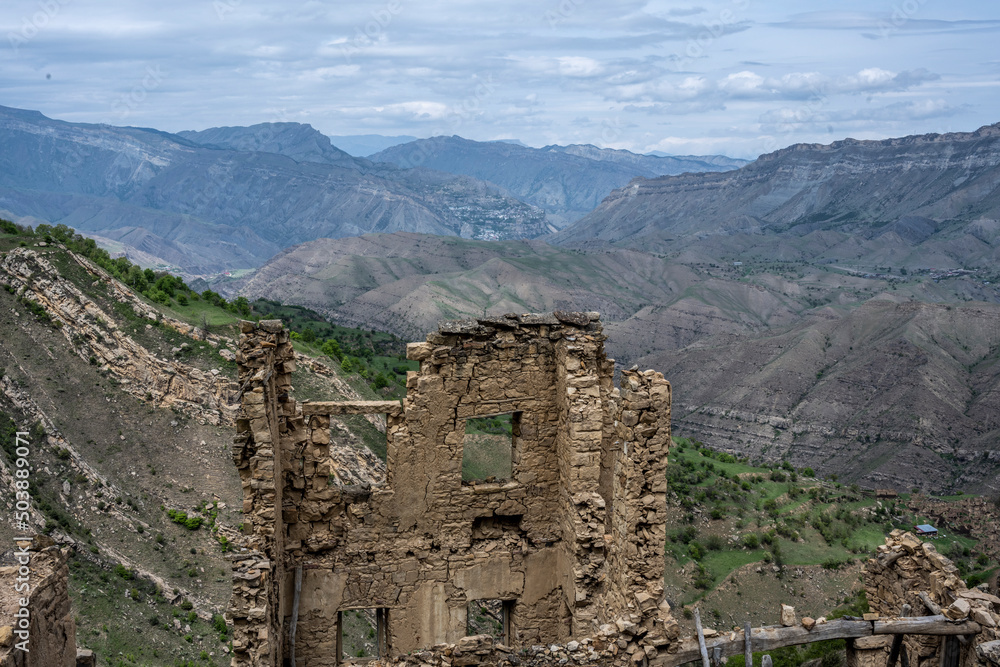 the ruins of an ancient alpine settlement in the mountains of Dagestan against the backdrop of mountains and blue sky
