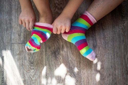 a girl tries on two socks with rainbow colors on different legs as a symbol or concept of the lgbt community