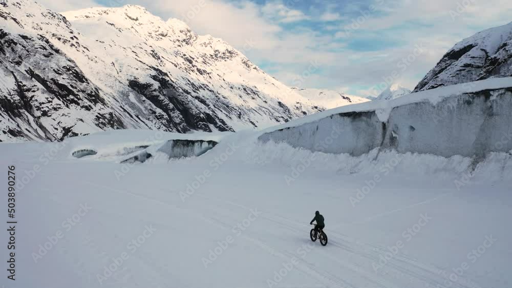 Following drone shot Above a Fat Tire Bike then pulling away to a height that show large ice bergs and the Valdez Glacier. Following drone shot Above a Fat Tire Bike then pulling away to a height that show large ice bergs and the Valdez Glacier.