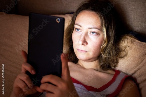 a young woman hides in bed at night and secretly spoils her eyesight watching movies on her phone
