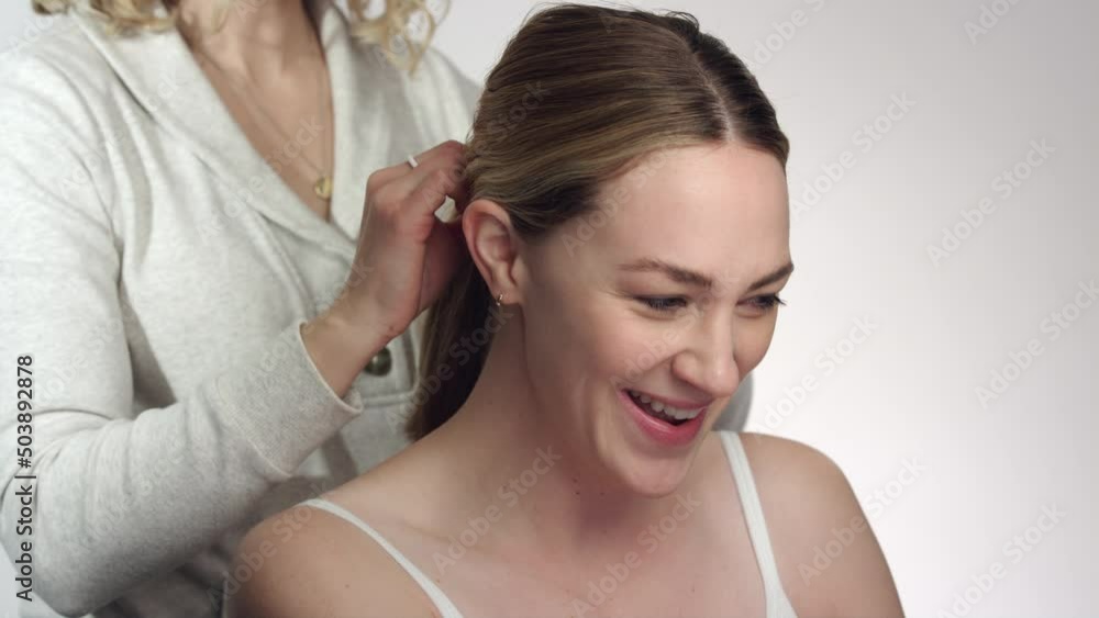 Pretty caucasian model chats and laughs with hair stylist fixing hair Pretty caucasian model chats and laughs with hair stylist fixing hair