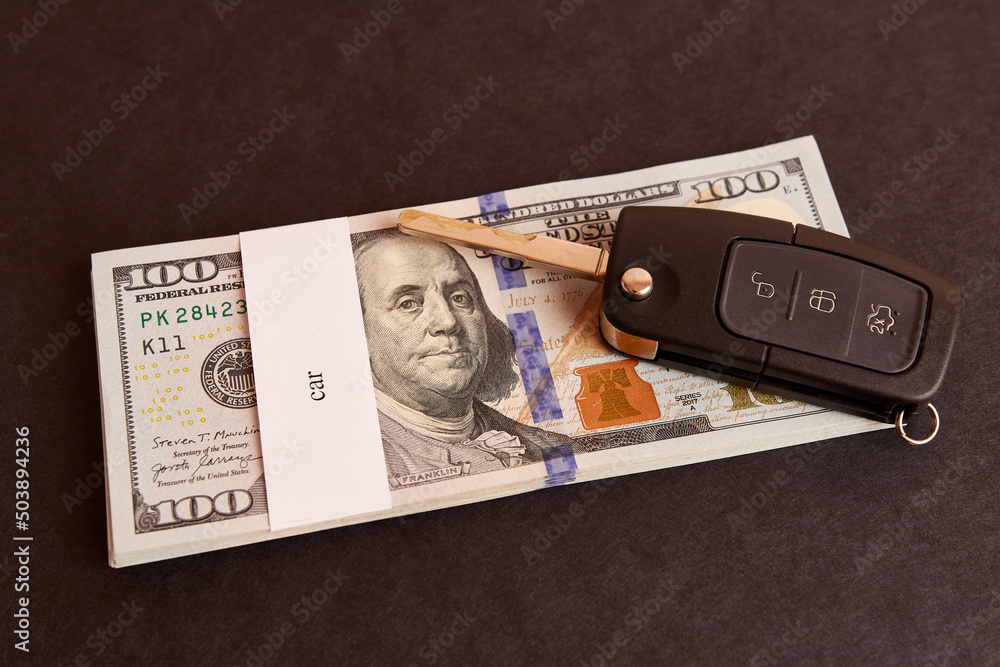 Naklejka premium Bundle of dollars with the inscription car and car keys on a black background. Car buying concept.