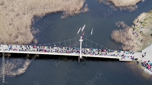 Top down view of following the canoes and kayaks on a river. Competition with boats. Water sports. Pro athletes competiting with eachother. People standing on abridge and looking photo