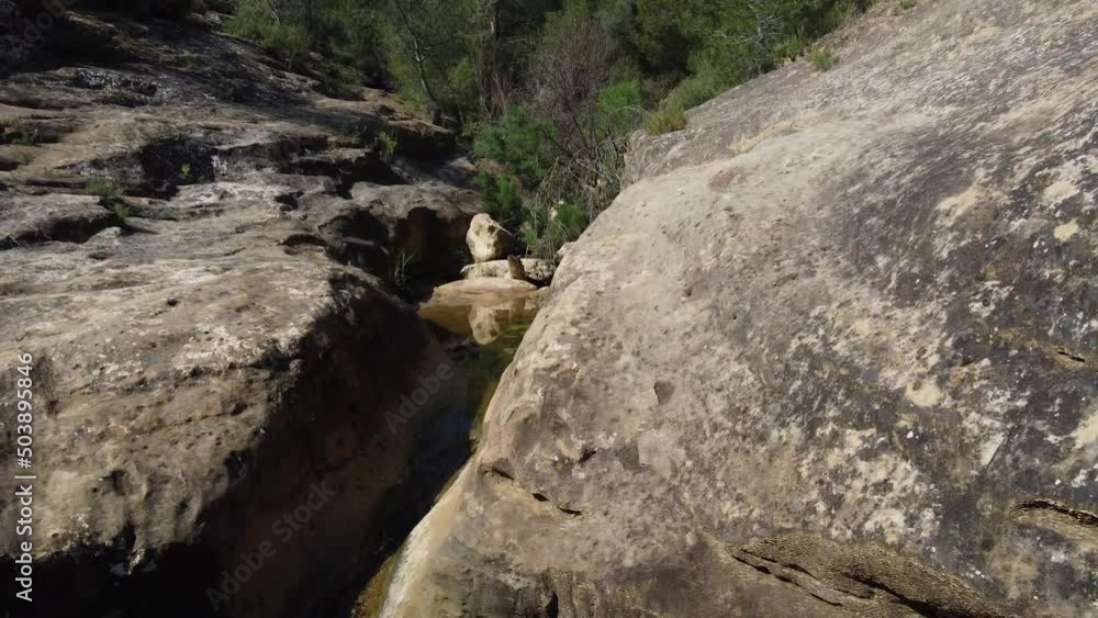 A small creek trickles down the canyon and through Giant's Cauldron in Algorfa Alicante, Spain - ascending aerial view A small creek trickles down the canyon and through Giant's Cauldron in Algorfa Alicante, Spain - ascending aerial view