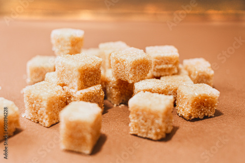 Brown sugar cubes close up on brown paper background