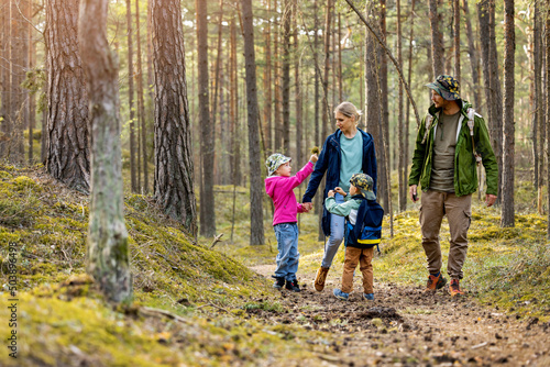 young family walking and exploring the forest with children. nature adventures