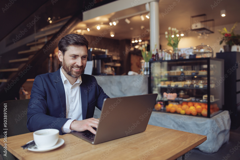 Caucasian attractive man sitting at table and texting on laptop in luxury cafe. Freelancing work. Caucasian attractive man sitting at table and texting on laptop in luxury cafe. Freelancing work.