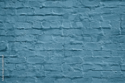 Old messy plastered exterior brick wall texture. Dark blue painted aged rough brickwork masonry grunge background