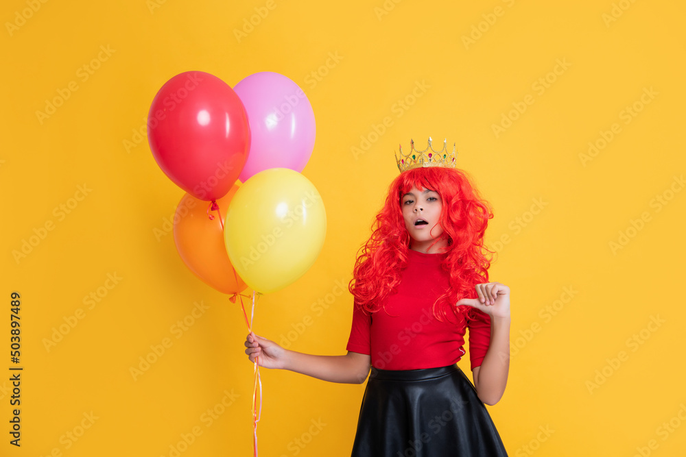 Fototapeta premium surprised child in crown with party balloon on yellow background