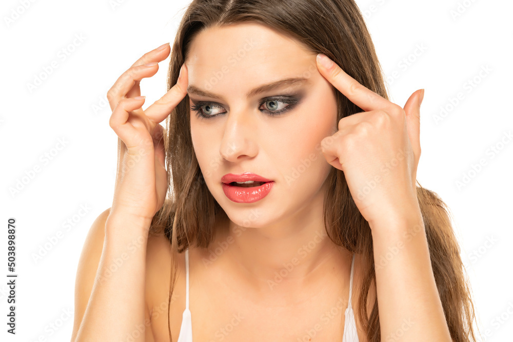young woman tightens her eyes and eyebrows in the mirror on a white background young woman tightens her eyes and eyebrows in the mirror on a white background
