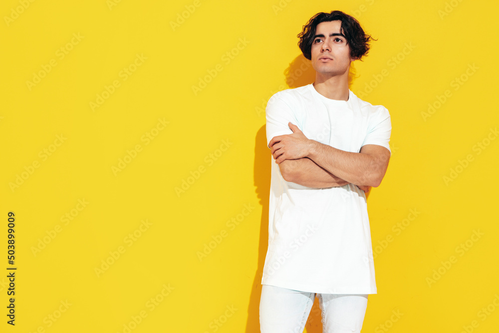 Portrait of handsome confident stylish hipster lambersexual model.Sexy man dressed in over size T-shirt and jeans. Fashion male isolated in studio. Posing near yellow wall Portrait of handsome confident stylish hipster lambersexual model.Sexy man dressed in over size T-shirt and jeans. Fashion male isolated in studio. Posing near yellow wall