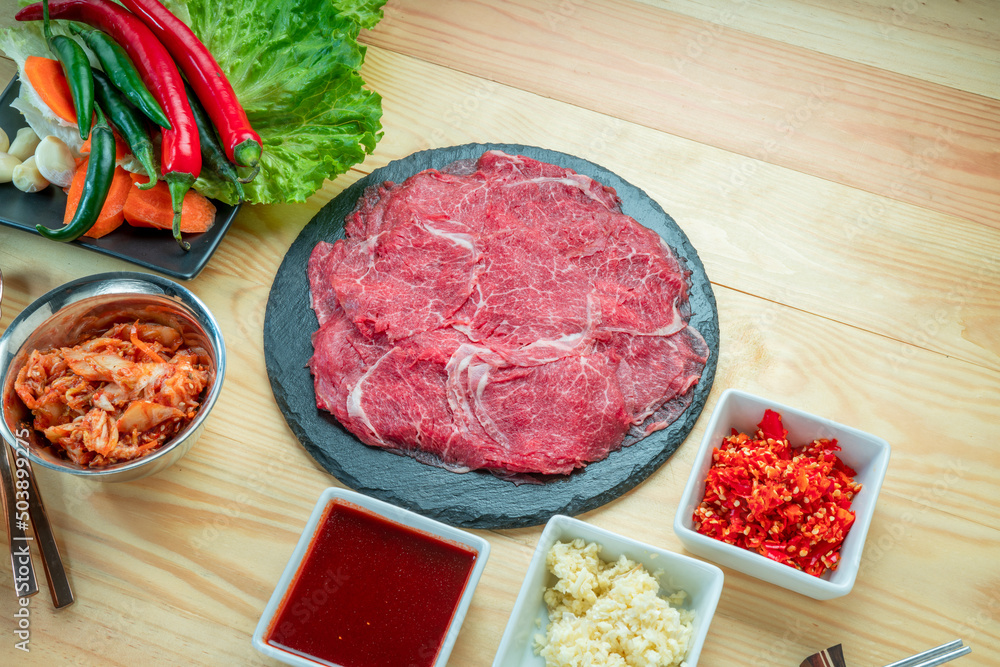 Rare Sliced Wagyu beef with marbled texture on black plate, Meat red beef on wooden background, Asian shabu shabu Sukiyaki food style. Rare Sliced Wagyu beef with marbled texture on black plate, Meat red beef on wooden background, Asian shabu shabu Sukiyaki food style.