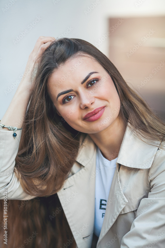 Portrait of a young beautiful long-haired woman in a European city. A model in stylish casual wear is relaxing outside. Portrait of a young beautiful long-haired woman in a European city. A model in stylish casual wear is relaxing outside.