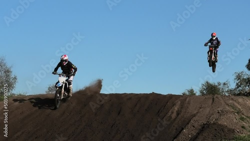 Dirt bikes jumping on motocross circuit in Arnhem, the Netherlands, with visiible hill photo