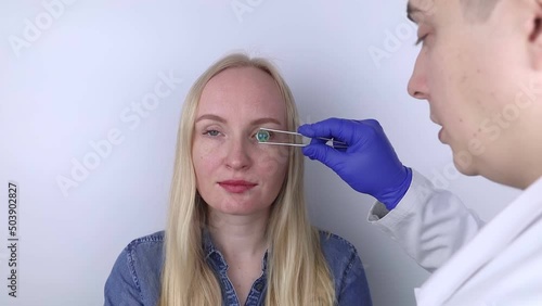 Conceptual shot of an eye crystalline lens replacement. Ophthalmic surgery. Return of sight. Removal of cataracts. Surgical intervention in the eyeball. Doctor holds the implant near the patient