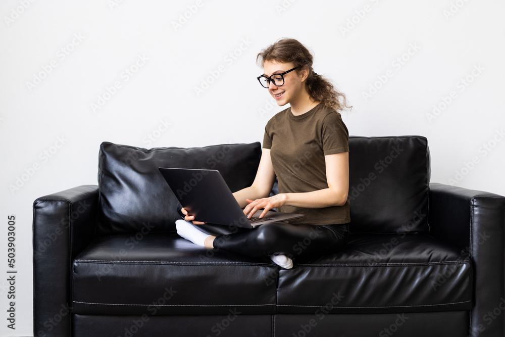 Pensive young woman using laptop computer while sitting on a couch at home Pensive young woman using laptop computer while sitting on a couch at home