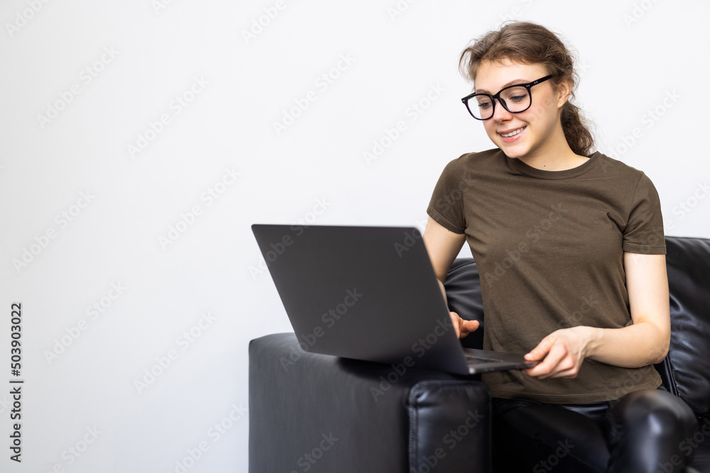 Young woman using a laptop while relaxing on the couch Young woman using a laptop while relaxing on the couch