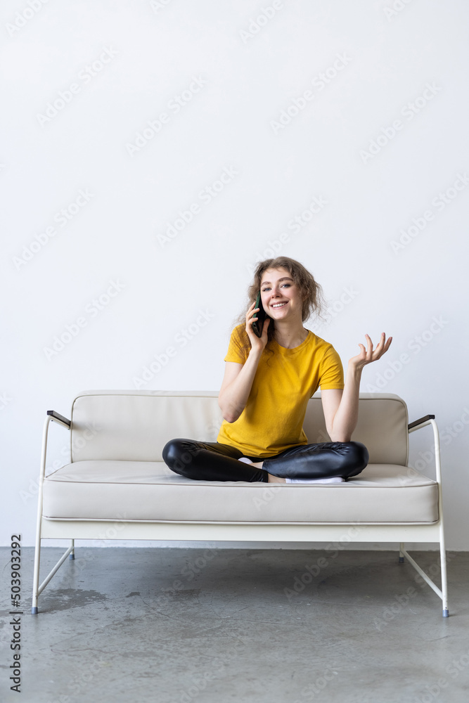 Young cheerful woman in couch talking on mobile phone on couch Young cheerful woman in couch talking on mobile phone on couch