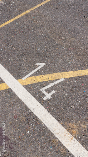 Numero 14 y lineas pintura blanca y amarilla en suelo de asfaltod e parking