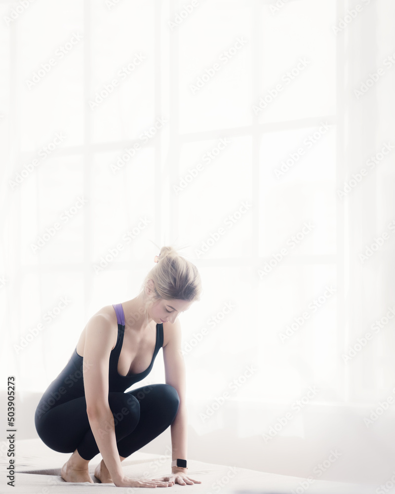 Beautiful sporty blonde exercising on yoga mat in living room Beautiful sporty blonde exercising on yoga mat in living room