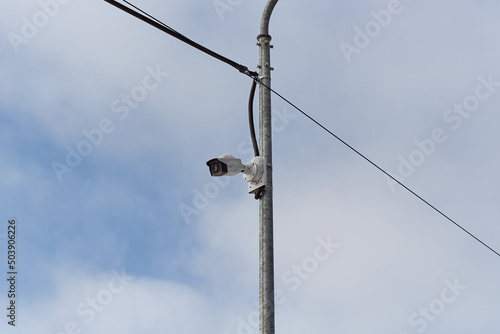 Surveillance camera on a metal pole on background sky