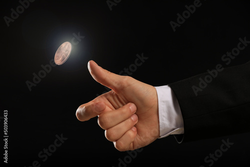 Man throwing coin on black background, closeup. Making decision Fototapet
