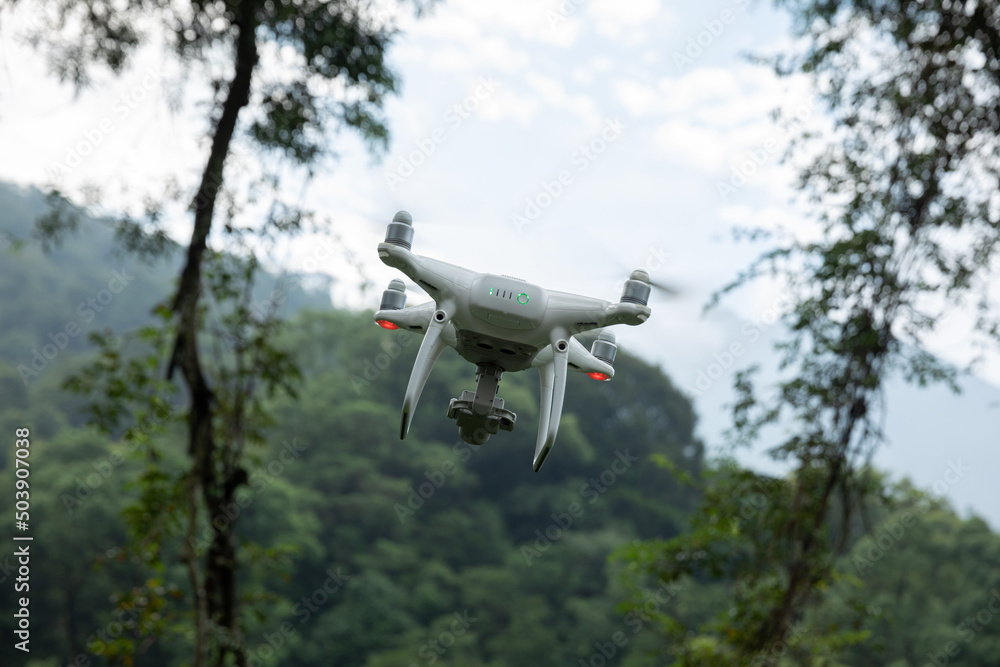 White drone with camera flying in summer forest White drone with camera flying in summer forest