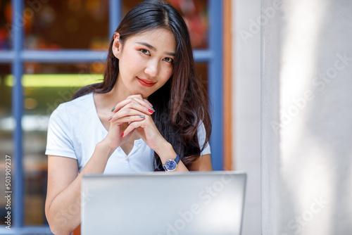 Charming young Asian woman working at the office using a laptop Looking at the camera.