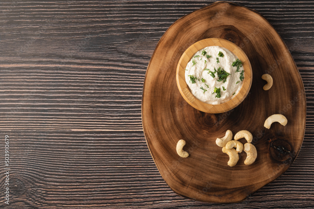 Vegetarian cream cheese made from fermented cashews on dark wooden background. Copy space. Vegetarian cream cheese made from fermented cashews on dark wooden background. Copy space.