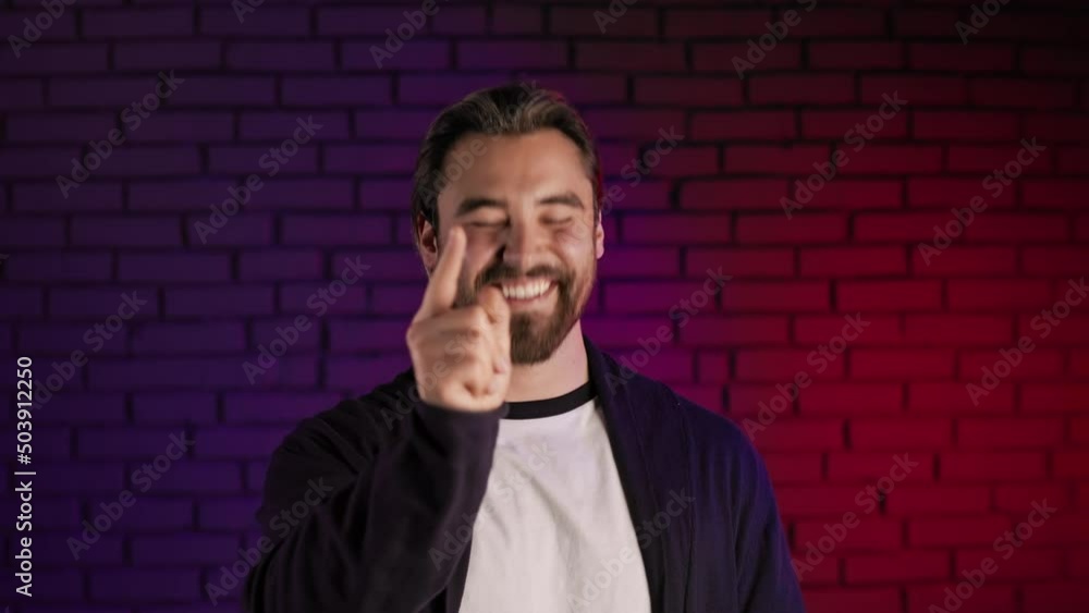 Portrait of smiling bearded man pointing with finger and clapping in hands while standing in studio with neon light around. You are right gesture. Portrait of smiling bearded man pointing with finger and clapping in hands while standing in studio with neon light around. You are right gesture.