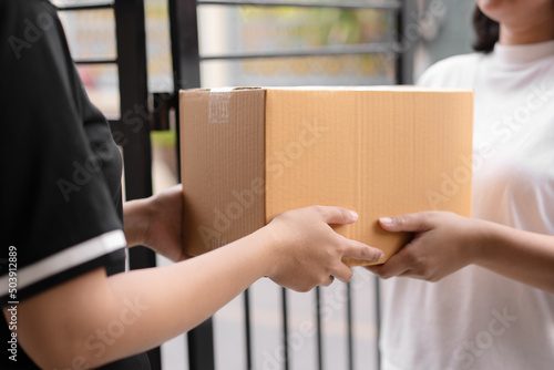 Postal service sending paper cardboard box to customer in front of a house outdoor. Shipping service arrival and send to customer address.