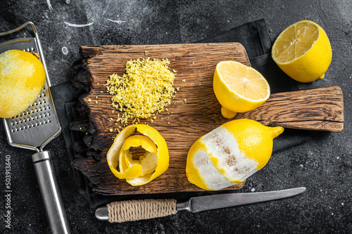Grated Lemon Zest and spiral peel on wooden board. Black background. Top view photo