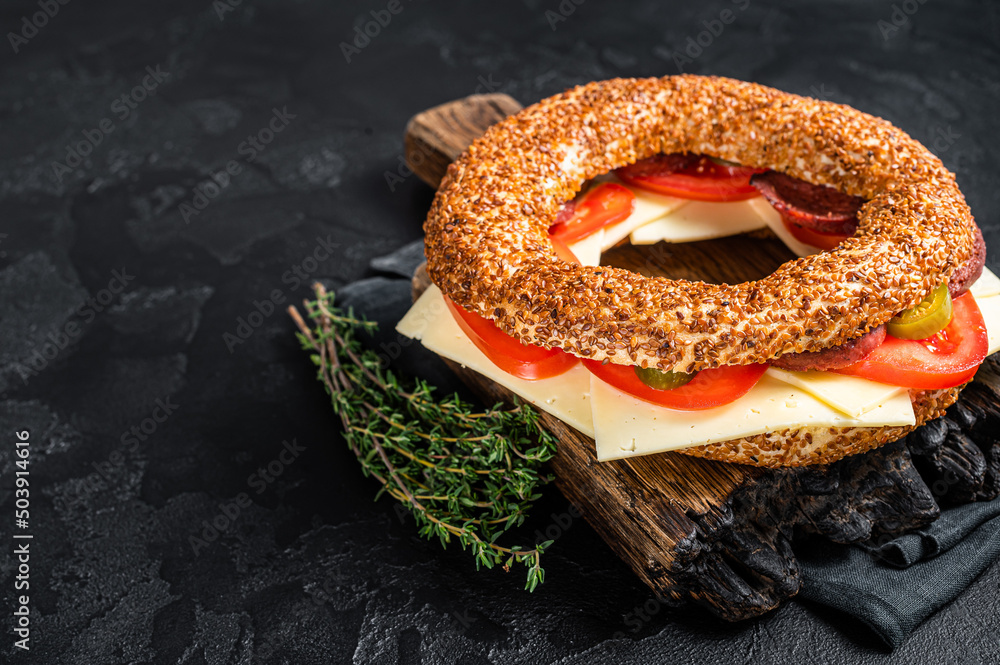 Simit bagel sandwich with lettuce, tomato, yellow cheese and ham. Black