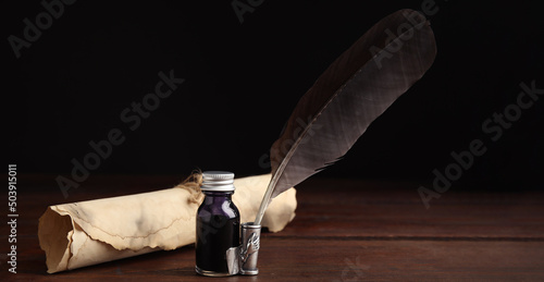Quill, bottle of ink and parchment scroll on wooden table. Banner design